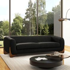 a living room with a black couch and coffee table in front of large glass windows