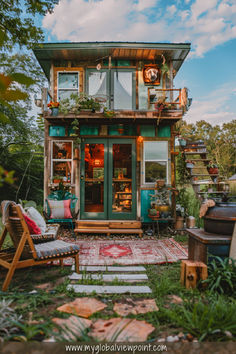 A whimsical two-story Airbnb tiny home in Tennessee, surrounded by lush greenery and decorated with vibrant plants, fairy lights, and cozy outdoor seating. The rustic wooden design, warm interior lighting, and boho decor create a charming and inviting atmosphere.