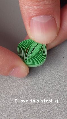 a person's finger with a green ring on it