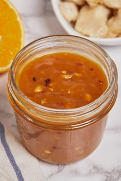 a jar filled with sauce next to an orange