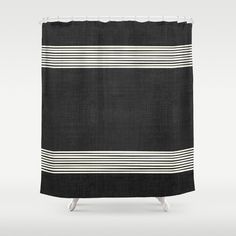 a black and white shower curtain with horizontal stripes on the bottom, in front of a gray background