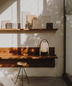 a table with a lamp and some books on it in front of a white wall