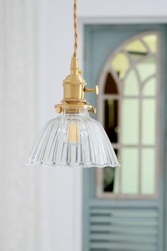 a light fixture hanging from a ceiling in front of a door with a window behind it