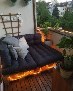 a couch with lights on it is sitting on the roof deck in front of some potted plants