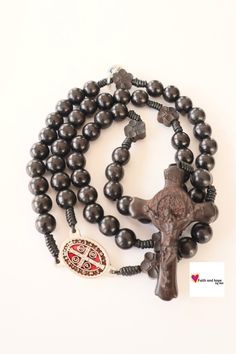 A beautiful black wood rosary makes a meaningful and beautiful gift for a first communion, or confirmation. Also perfect gift for a father or husband. Devoted to St Benedict with wood crucifix, accented with flower shaped beads. A nice piece to accent your spiritual life, or the life of a loved one! Specifications: Length: 20 in beads -  8 mm God Bless you! Note: The colors of the rosary may vary slightly from the photo Black Cross Rosary As Gift, Black Crucifix Rosary As Gift, Black Wooden Beads Rosary Spiritual Style, Black Wooden Beads Spiritual Rosary, Black Wooden Beads Rosary, Rosary Gift, San Jacinto, Orange Agate, Saint Benedict