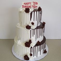 a three tiered birthday cake with chocolate icing and flowers