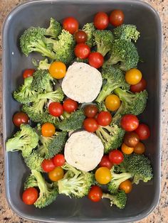 a bowl filled with broccoli, tomatoes and other veggies on top of a table