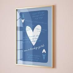 a framed blue and white heart on a pink wall with handwritten text below it