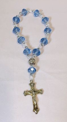 6” Rosary Overflowing Blue-Transparent Multifaceted Glass Beads and Crucifix This beautiful 6-inch bracelet is perfect for any occasion, whether it's Mother's Day, Christmas, birthdays, Valentine's Day, or Confirmation/Communion. The bracelet features 11 stunning blue and multicolored glass beads in a round shape, each measuring .375 inches in width, and one metal bead. The 11 blue beads are multifaceted, adding an extra touch of elegance. The bracelet also has a charming crucifix as a centerpiece, to complete the religious theme. It is held all together by elastic material for a comfortable fit making it easy to slip-on and pull-off. This item is perfect for those who love religious-themed jewelry and makes a great gift. Rosary stretch bracelet, with blue main beads with silver beads in b Rosary Bracelet Diy, Diy Rosary Necklace, Rosary Ideas, Diy Rosary, Beautiful Rosaries, Catholic Rosary Bracelet, Prayer Jewelry, Chaplet Rosary, Mini Rosaries