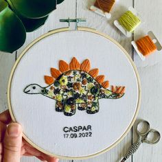 a hand embroidered dinosaur with flowers on it