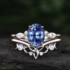 a tan gold ring with a blue sapphire and diamond accents on it, sitting on a piece of wood