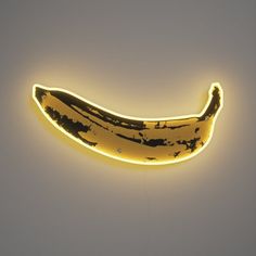 a lighted banana hanging from the side of a wall in front of a white background