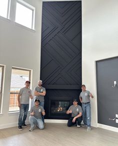 four men are standing in front of a fireplace