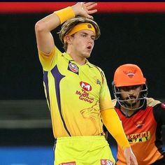 two men in yellow and orange uniforms are playing cricket