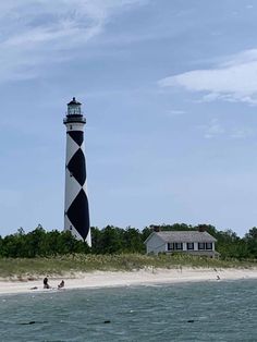 a black and white lighthouse sitting on top of a sandy beach