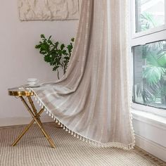 a room with a large window and a white drape on the wall next to a small table