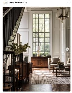 a living room filled with furniture and a stair case in front of a large window