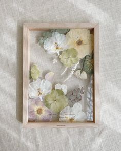 a shadow box with flowers in it on a bed