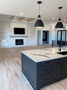 a large kitchen with an island in the middle and two pendant lights hanging from the ceiling