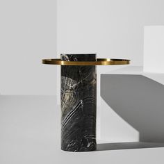 a black and white marble table with gold trim around the edge, in front of a white wall