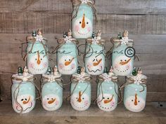 there are many snowmen painted on mason jars