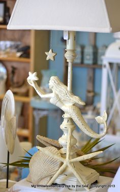 a lamp that is sitting on top of a table next to a sea shell and starfish