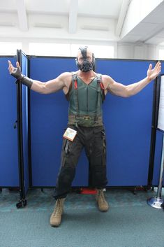 a man dressed in costume standing next to blue partitions with his arms stretched out