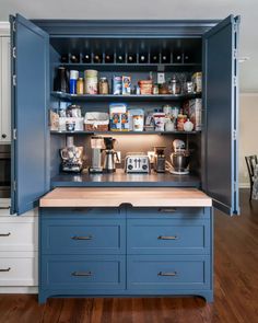 an open cabinet in the middle of a kitchen with lots of counter space and cupboards