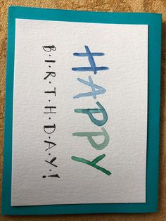 a card with the words happy birthday written in blue, green and purple on it