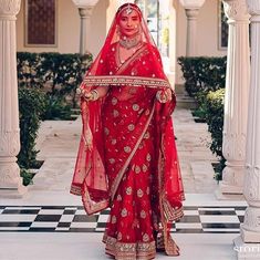 a woman in a red bridal gown standing on a checkered floor with columns