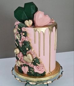 a pink and gold decorated cake on a stand