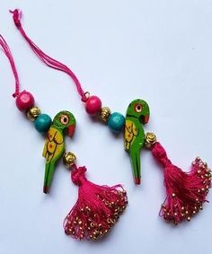 two parrots with beads and tassels hanging from it's sides on a white surface