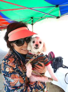 a woman holding a small dog under an umbrella