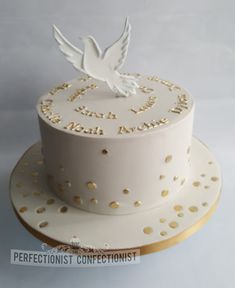 a white cake with gold dots and a dove on top