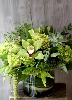 a vase filled with green flowers and greenery