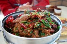 a large pot filled with meat and vegetables on top of a table next to other plates