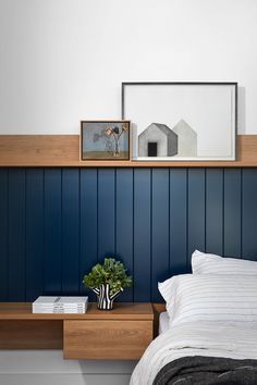 a bedroom with blue painted walls and white bedding, two framed pictures on the wall