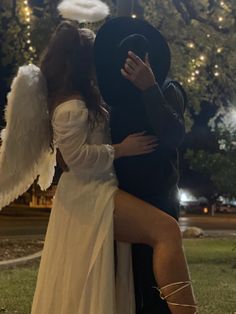 a man and woman dressed up as angels hugging each other in the park at night