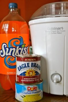 some orange juice and other items on a wooden table next to a white blender