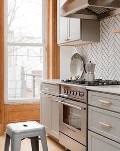 a stove top oven sitting inside of a kitchen next to a window with wooden trim