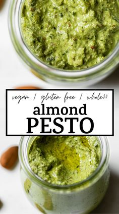 two jars filled with green pesto on top of a white table next to almonds