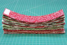 a stack of red and green fabric sitting on top of a cutting board