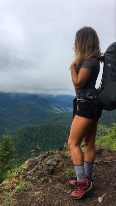 a woman standing on top of a mountain with a backpack