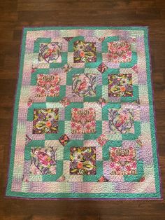 a pink and green quilt on the floor