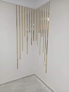 a room with white walls and wooden sticks hanging from the ceiling