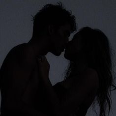 a man and woman kissing in the dark with their hands on each other's chest