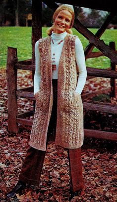 a woman standing in leaves wearing a knitted vest