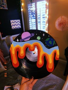 a person holding up a record with an image of the moon and planets on it