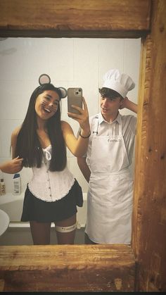 two people dressed up as chefs taking a selfie in front of a bathroom mirror