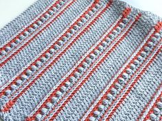 a crocheted dishcloth is sitting on a table with an orange and gray stripe